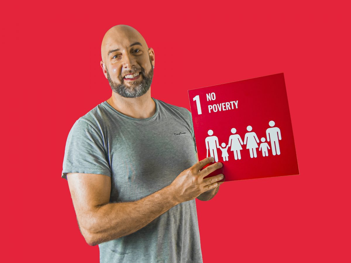 Man holding up sign showing Global Sustainable Development Goal 1, no poverty.