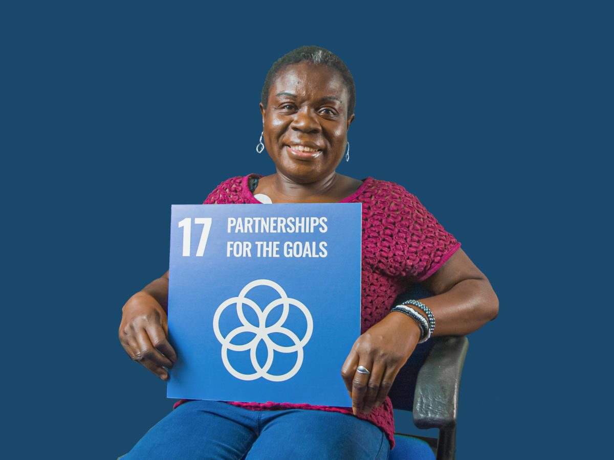 Woman holding up sign showing Global Sustainable Development Goal 17, partnership for the goals.