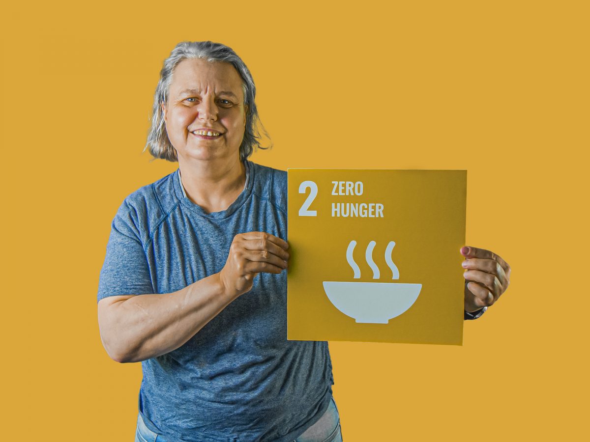 Woman holding up sign showing Global Sustainable Development Goal 2, zero hunger.