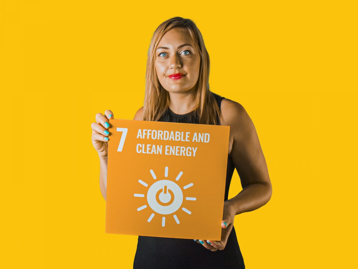 Woman holding up sign showing Global Sustainable Development Goal 7, affordable and clean energy.