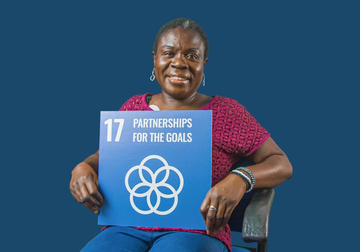 Woman holding up sign showing Global Sustainable Development Goal 17, partnership for the goals.